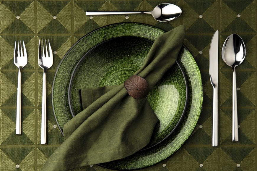 全绿色的餐桌，简单的棕色叶形餐巾环。