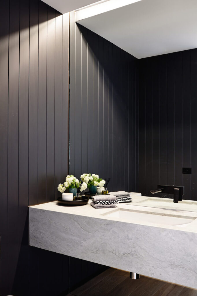 作为住宅的两个化妆室之一，这个浴室以深色木镶板和白色花岗岩浮动台面为特色。高端的当代装置增添了额外的奢华。