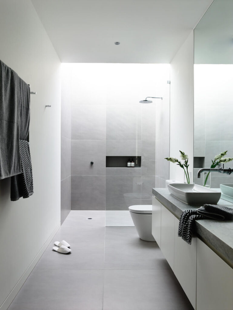 换个角度看，瓷砖似乎变成了浅灰色。在浴缸的另一端是一个大的玻璃淋浴房和便盆。
