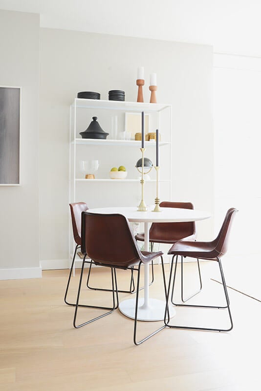 餐桌完美地集中了开放式空间，以极简主义的方式包含了整个室内的元素。靠墙的白色书架上摆放着小摆设和艺术品，为房间增添了细节和色彩。