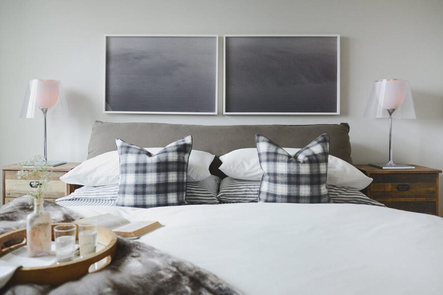 代替传统的床头板，主卧室的双窗框黑色染色木材，与白色墙壁形成鲜明对比。