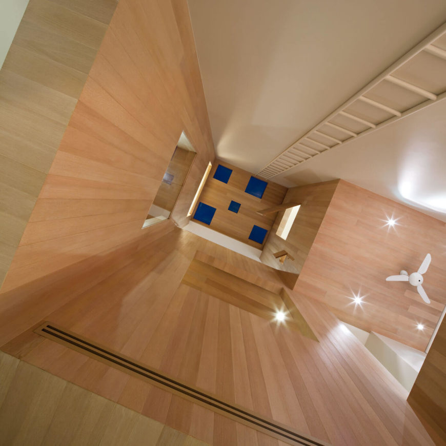这是住宅中心巨大的三层空间的向上视图，瞥见隐藏的面板，小隔间和点缀在内部的阁楼空间。天然木材和超现代形状的混合使一种清新的风格。