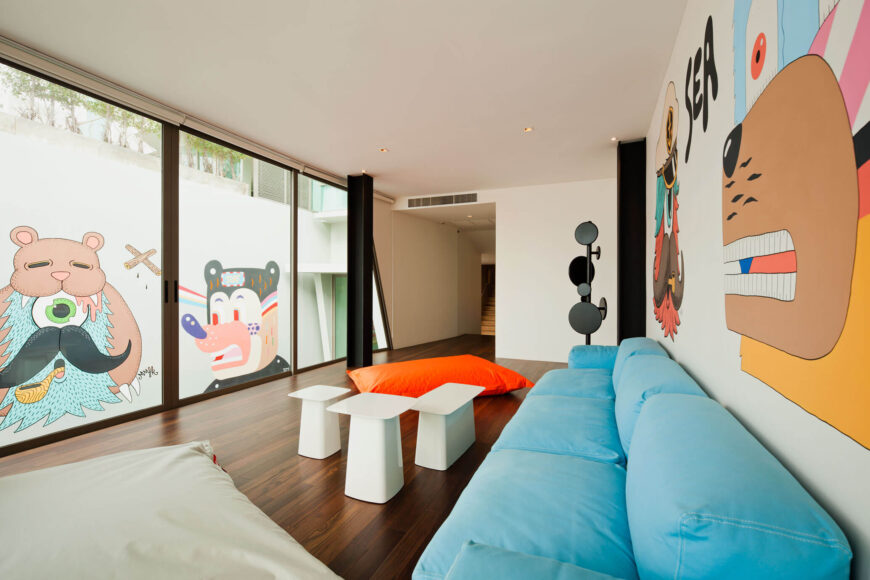 主题涂鸦装饰了整个家庭的大空间，为时尚的现代空间增添了个性和细节。天蓝色的沙发和一套纯白色的咖啡桌与黑色的工字梁和白色的墙壁相辅相成。