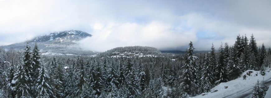 与上图相同的基本镜头，展示了冬季的景观。许多山被厚厚的云层遮住了。在夏季的森林里，任何建筑物在下雪的时候似乎都消失了。