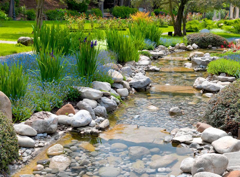 这个带有亚洲风格池塘的令人愉快的花园邀请任何路过的人停下来享受跳过一些岩石，蘸着脚趾头，或者只是简单地休息一下，欣赏所有这些美丽。