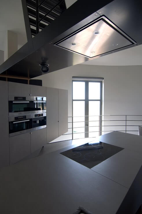 仔细观察厨房，可以发现光滑的白色极简主义台面和橱柜。高端电器整齐、无缝地包含在橱柜中。