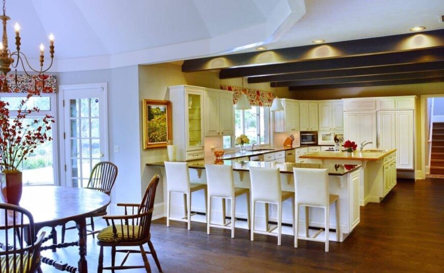 厨房本身是一个巨大的开放式设计，光滑的台面和暴露的架空横梁界定了烹饪区。一排白色的吧台凳坐落在封闭的台面上，提供了充足的用餐空间。