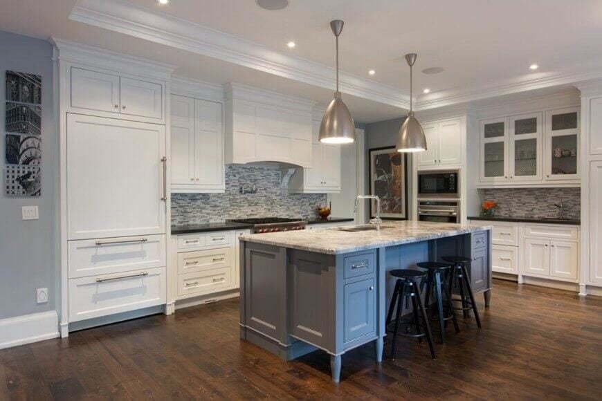 这间厨房以清爽的白色橱柜为特色。地板是光滑的硬木，与拉丝不锈钢灯具的精致照明相呼应。