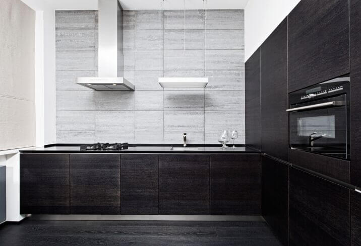 这个华丽的厨房设计在后挡板和深色橱柜和台面之间形成了丰富的对比。造型大胆而现代，在柔和的光线下看起来很时尚。