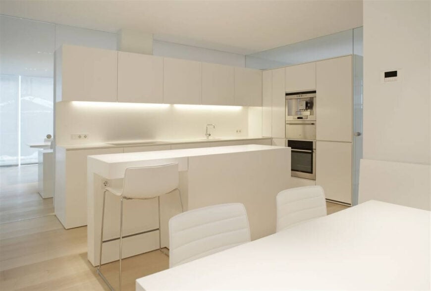 这个简约的厨房有华丽的光滑的白色台面和橱柜。柜内照明带出柔和自然的光芒。