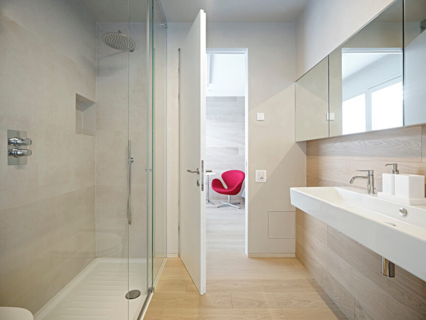 两间浴室中的第一间设有淋浴间和宽敞的水槽区，颜色轻盈;让空间感觉更大，同时保持小而实用。