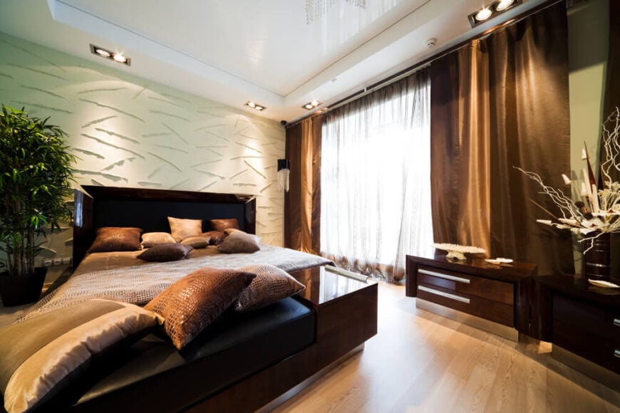 这个卧室空间是关于质感的!在这种情况下，带有干净线条和金属装饰的深色现代家具屈居次要地位。独特质感的奶油色墙壁、蛇皮抱枕和被子，以及奶油色和棕色的前卫布置，与光滑的浅色硬木地板、柔软流畅的窗帘和时髦的现代家具线条形成了无可挑剔的对比。