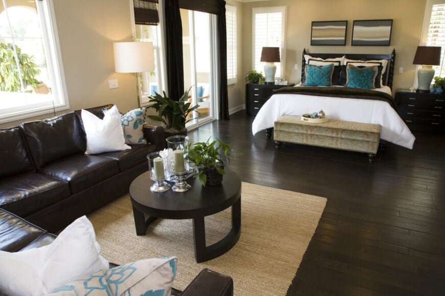 这间卧室的特色是奶油色的墙壁，充足的自然光，令人惊叹的深色硬木地板与家具完美协调。一块质地轻盈的小地毯打破了原本可能过于黑暗的造型。大胆的蓝绿色和明亮的白色与深色截面、茶几、床和其他家具形成鲜明对比。
