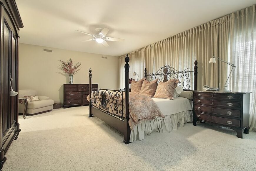 这个卧室是使用浅色的另一个很好的例子，利用家具和周围环境之间的鲜明对比来达到很好的效果。地毯、墙壁、躺椅和较轻的亚麻布几乎融合在一起。深色图案的羽绒被套和抱枕与各种浅米色的色调相得益彰。一张四柱床，配有华丽的金属床头板和踏板，与卧室其他家具的古色古香的外观完美搭配。现代台灯看起来几乎不合适，但不知何故，它与这个简单而华丽的卧室完美地搭配在一起。