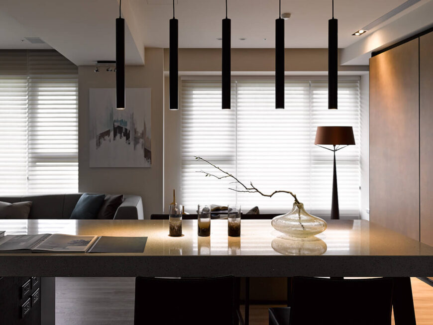 五个细长的圆柱形吊灯是众多创新照明元素之一，旨在强调这个家居设计的高度功能性现代性质。