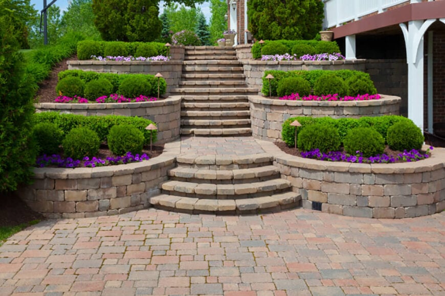 这个砖砌的露台让人想起一个大庄园的入口。丰富的绿色树叶和色彩鲜艳的花朵形成了可爱的对比。