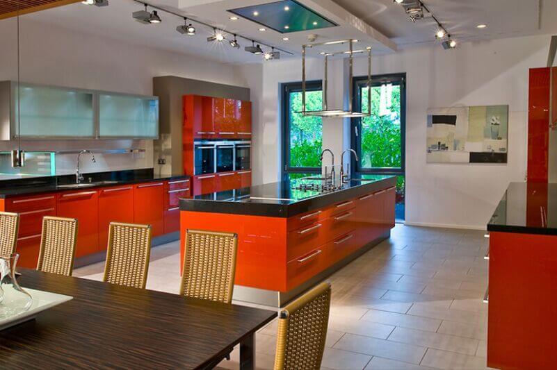 这个超现代的厨房充满了色彩和对比，亮红色的橱柜和深色的台面。大岛台设有双水槽和内置灶台。