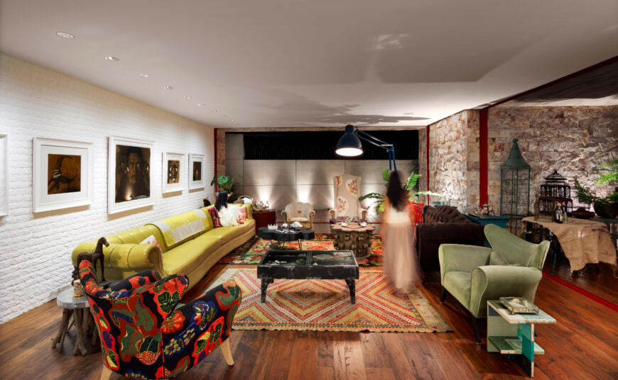 住宅中心的客厅充满了激进的色彩和高对比度的纹理元素。石墙与硬木地板竞争，而令人眼花缭乱的家具类型充斥着布局。