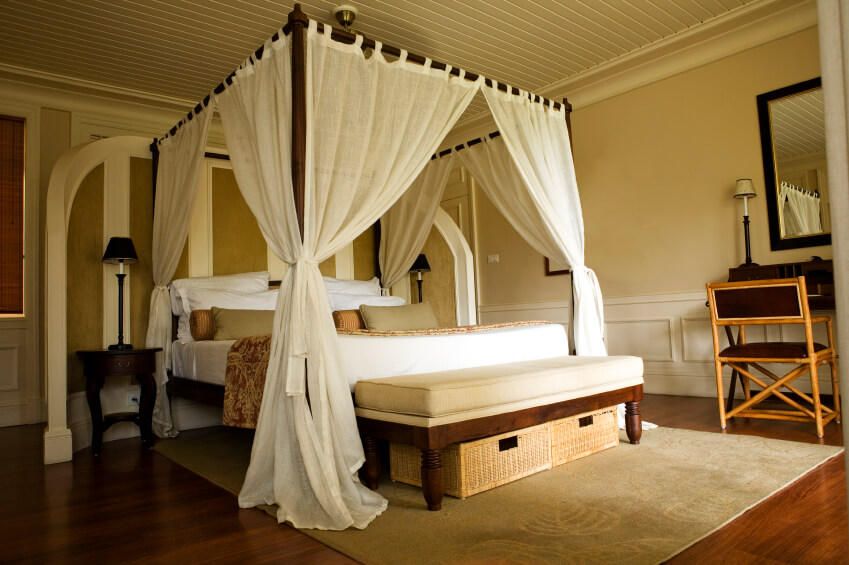 浅色的棉质窗帘为这间可爱的主卧室增添了热带风情。一面四分之三的弧形墙将门口与卧室的主要部分隔开。