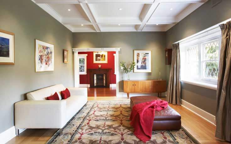 绝对华丽的格子天花板，嵌入式照明，为这个小的起居区带来优雅。圣人墙为房间带来传统的中性舒适，而大胆的红色与大面积地毯和相邻的深红色入口相连。