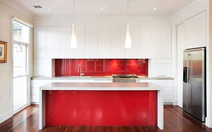这个光滑的现代红色厨房配有不锈钢电器和明亮的白色橱柜，它的功能和它的美丽一样。糖果苹果红岛与充满活力的后挡板相匹配，是准备家庭膳食的完美选择。