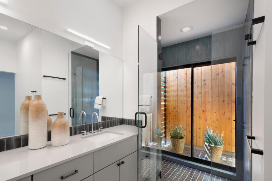 浴室具有超现代的外观，光滑的橱柜，瓷砖地板，和玻璃封闭的淋浴。一组滑动玻璃门可以直接进入庭院。