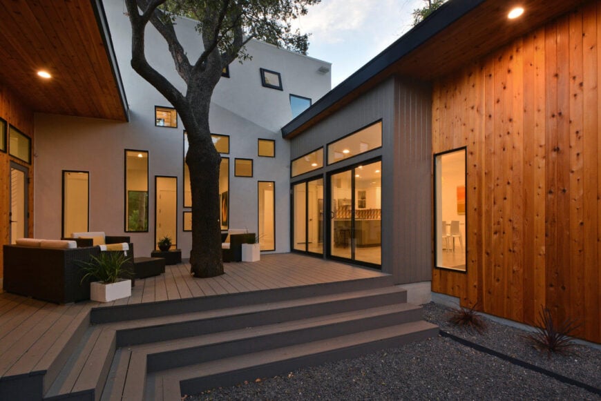 大面积的灰色、天然木材和白色之间的对比，在庭院周围创造了一个模糊的调色板。充足的窗户扩展了室内和室外的视觉存在。