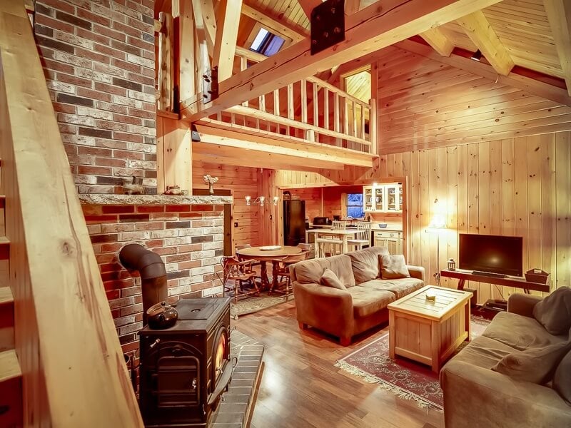 这间更加质朴的客厅以砖块、老式燃木炉和大量使用的松木为特色。拐角处是同样质朴但同样豪华的厨房。
