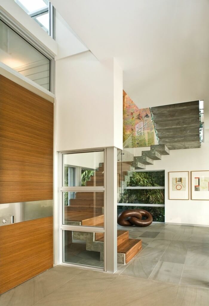 这个轻快的入口以浮动楼梯为特色，形成一个引人注目的陈述。所有的玻璃和开放空间都被用于左侧门和楼梯的异国情调的木材所温暖。
