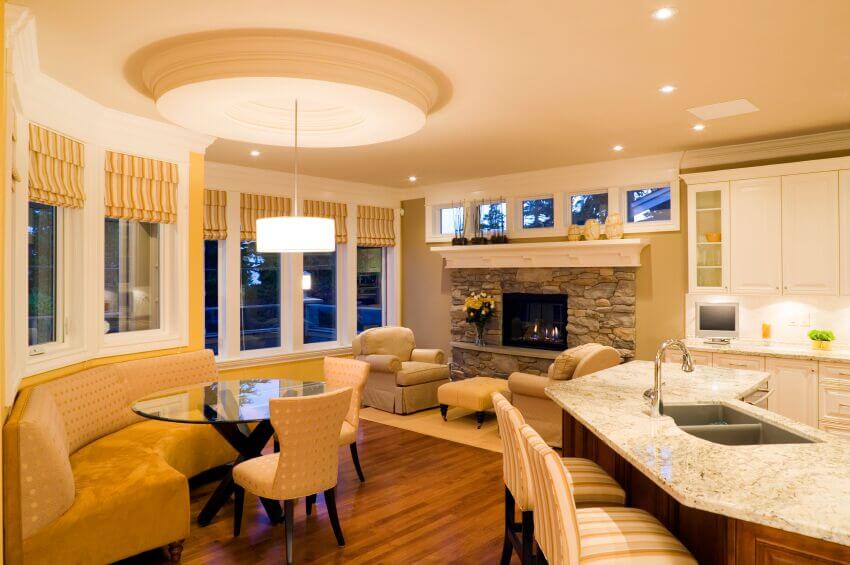 一个小客厅区与一个宽敞的白色厨房相连，也通往一个早餐角落，那里有一张圆形的玻璃桌和一个宽敞的长凳。