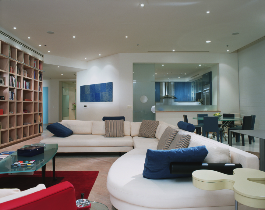 这个现代的家庭娱乐室用不同色调的舒缓蓝色创造了一个平静的空间。明亮的红色为整个房间增添了趣味，而大量的玻璃则创造了不同的纹理。