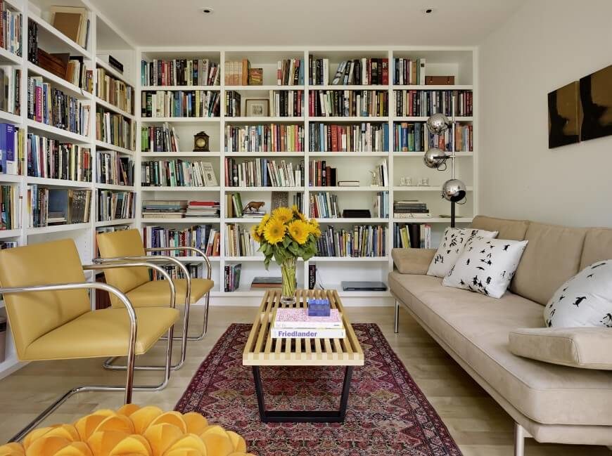 房间的另一端，从地板到天花板的书架在这个狭窄空间的白色墙壁上创造了存储空间和兴趣。中性和褪色的色调可以让书的颜色突出出来，为房间提供大部分的颜色。