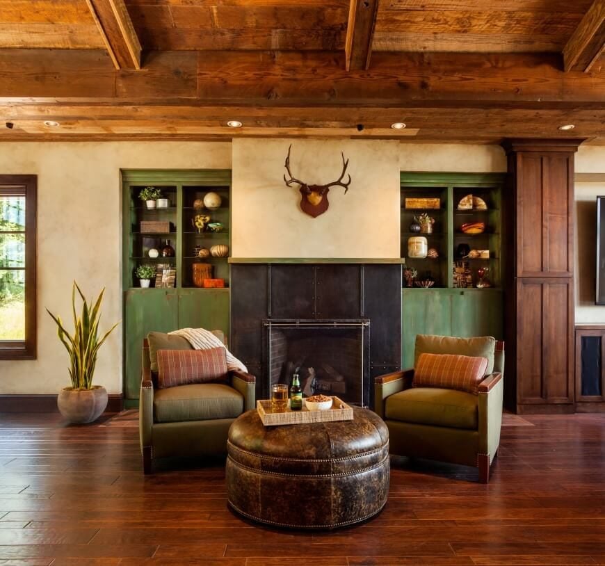 这个房间的绿色装饰与温暖的地板和破旧的皮革脚垫相得益彰。壁炉周围的金属镶板以其工业风格从房间的其他地方脱颖而出。