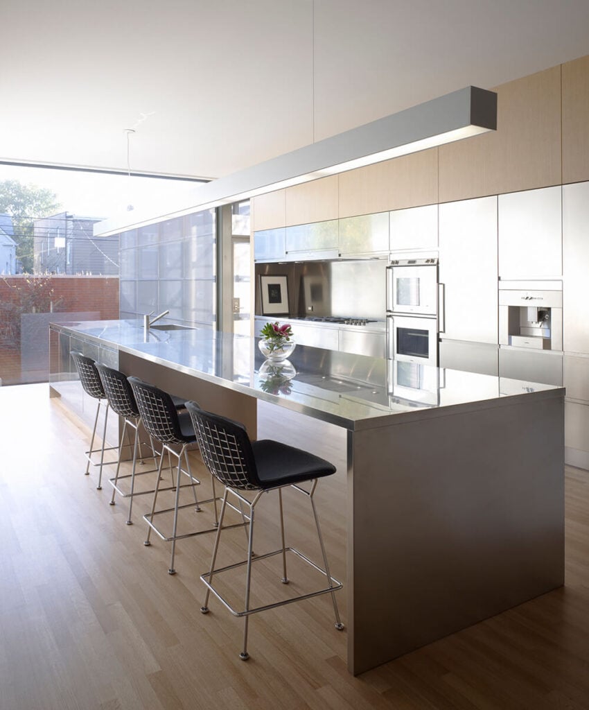 厨房是一处宽阔的开放式空间，铺着天然硬木地板和不锈钢，有一个足够大的岛台，可以容纳烹饪和用餐空间。金属橱柜有助于设置高对比度的基调。