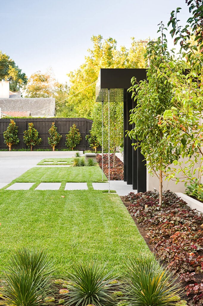 入口门,裹在黑色金属和两侧是一望无际的修剪整齐的草坪,站在鲜明的简单性。锋利的线条提示在现代建筑之家。