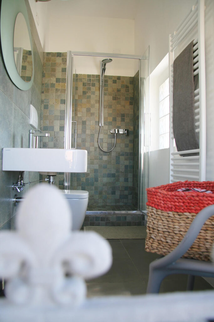 与主套房相连的整个浴室覆盖着一系列美丽的瓷砖和微妙的色彩。水槽和厕所的极简设计与形状独特的镜子相平衡。