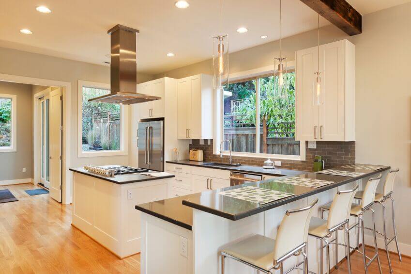 这个美丽明亮的厨房采用了当代厨房中流行的白色和灰色配色方案。光滑的橱柜与电器和花岗岩台面的干净边缘相得益彰。浅灰色的地铁地砖为空间增添了质感和趣味，而浅色木地板则为房间带来了温暖。