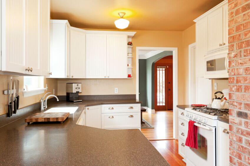 这个舒适的厨房通过使用浅色来让自己看起来不那么小。温暖的墙壁和木地板使房间看起来不那么生硬，而砖砌的强调墙为空间带来了兴趣。鲜亮的红色打破了主导的白色。