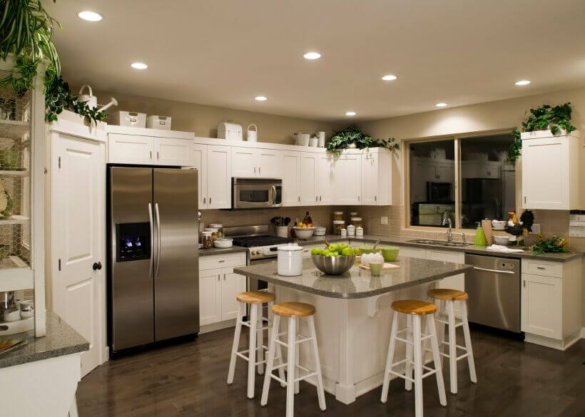 选择台面来补充电器和美丽的木地板给这个厨房一种统一和凝聚力的感觉。明亮的绿色和植物带来了简单的流行色，而白色的橱柜使房间明亮，即使在晚上。