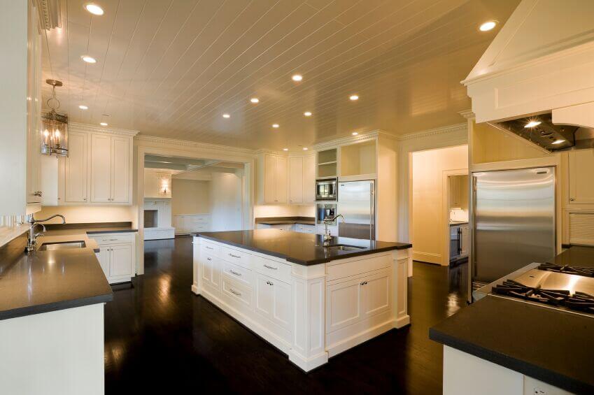 厨房里闪闪发光的深色木地板衬托出了深色花岗岩。白色橱柜和墙壁平衡了这一广阔的地板，使深色木材不会压倒房间，并确保房间保持开放和明亮。闪亮的不锈钢电器和配套的固定装置有助于照亮房间。在天花板上使用白色木镶板是一个有趣的转换，从标准的白色平顶天花板。