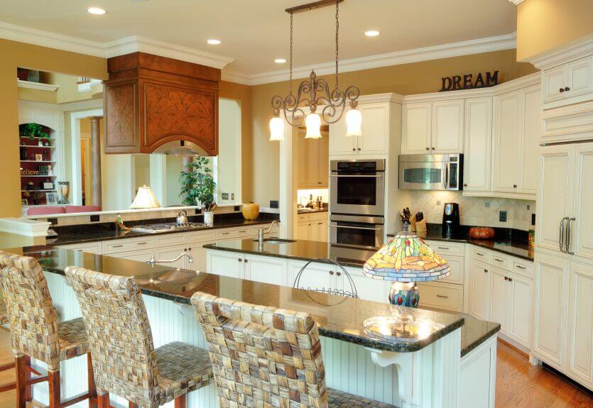 这个温暖舒适的厨房通过使用金色的墙壁和米白色的橱柜来实现。深色的柜台与电器相辅相成，而炉罩周围华丽的木制品则是房间其余部分的焦点。
