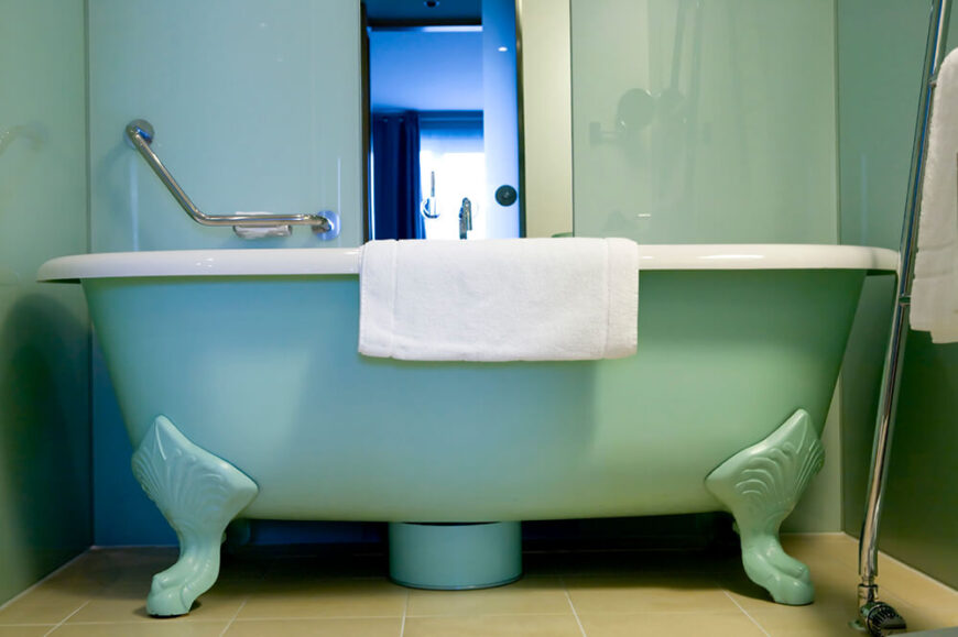 这是一个时尚而有点现代的空间，这个浴室有一个大的爪形管和铬手柄，方便访问。柔和的绿色与白色毛巾和浅色瓷砖地板搭配在一起，为房间定下了基调。