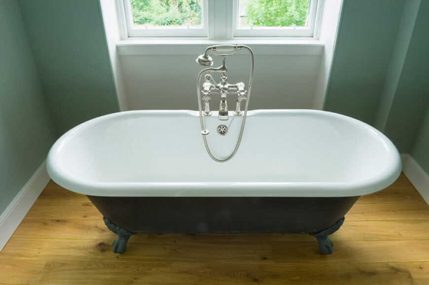 这个爪足浴缸可以容纳两个人，放在浅染色的硬木地板上。浴缸位于双层玻璃窗的中央，由洒进房间的自然光照亮。