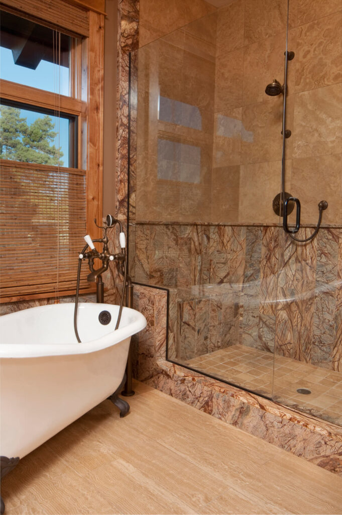 淋浴的外壳和内部复杂的纹理赋予了这个浴室空间的特点，当然也吸引了眼球。丰富的木窗框与石头相得益彰，而一个爪形浴缸则位于窗户下方的一个角度。