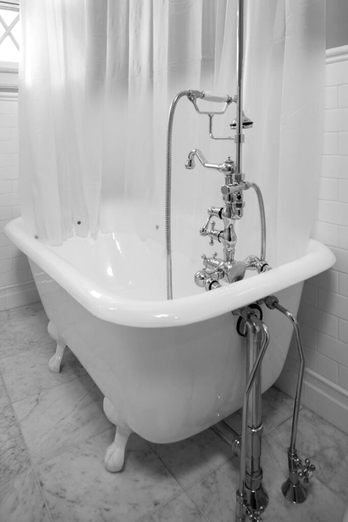 浴室的地板由有纹理的大理石组成，由带有瓷砖后挡板的纯白色墙壁构成。爪足浴缸有一个保护隐私的选项，如果不需要的话，也可以把它拉回来收起来。