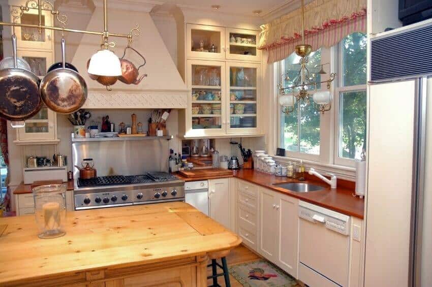 这个舒适的厨房利用一个单一的吧台作为锅架，而不是更常见的环形或矩形。它两端的灯与水槽上方的灯具相匹配，将整个厨房连接在一起。
