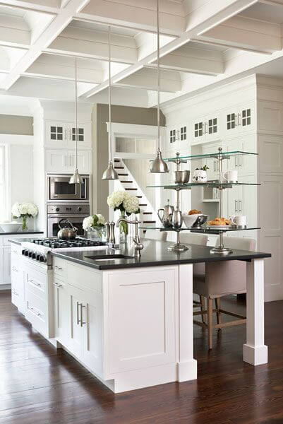 一个黑白相间的厨房，有玻璃架子，吊灯和优雅的格子天花板。