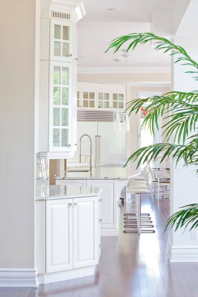 明亮的白色厨房，现代化的酒吧凳和豪华的水槽设置到大理石厨房岛。
