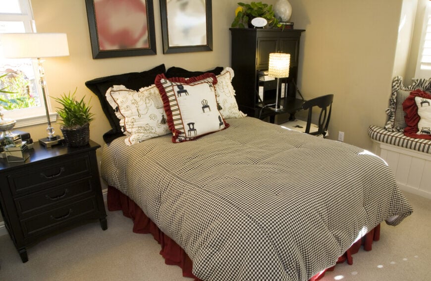 这间卧室的黑色、白色和红色配色与朴素的米色背景相衬，为这个房间增添了足够的趣味，不需要一个大胆的床头板。