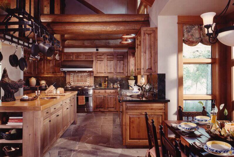 一个更乡村的厨房，有裸露的横梁，天然木橱柜，和一个长，全木制厨房岛，带一个小的中央洗涤槽。
